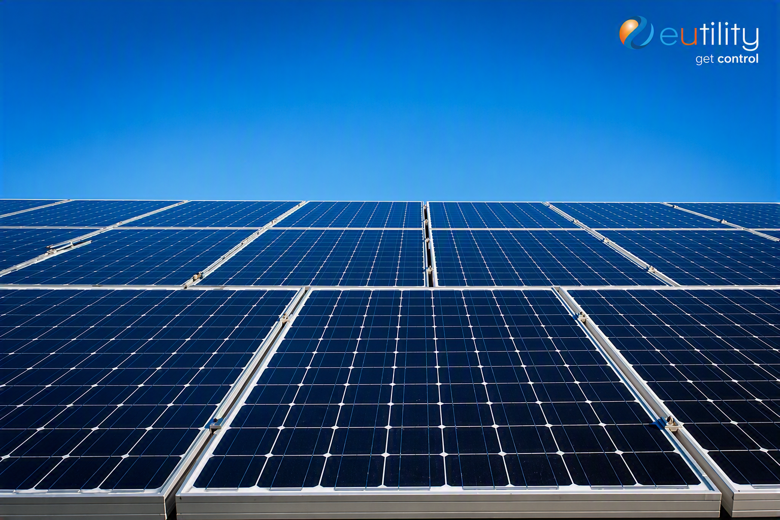 Rows of commercial solar panels photographed from below against a clear blue sky