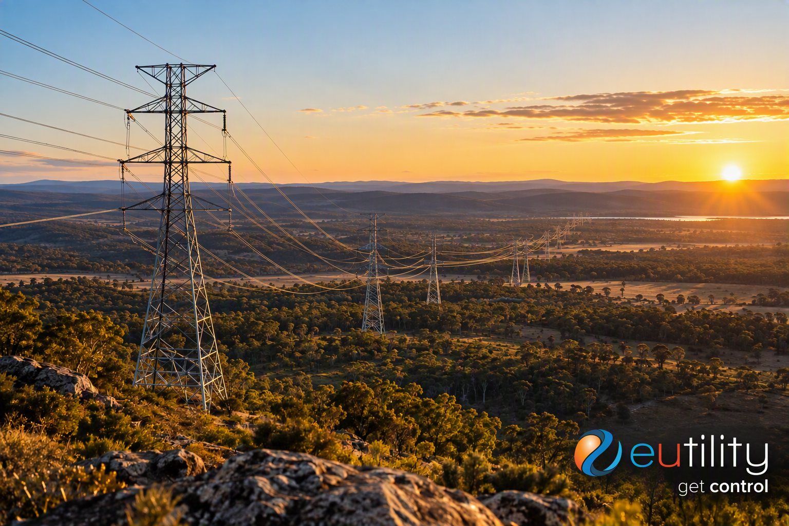 Transmission towers and power lines crossing Australian bushland towards the horizon at sunset